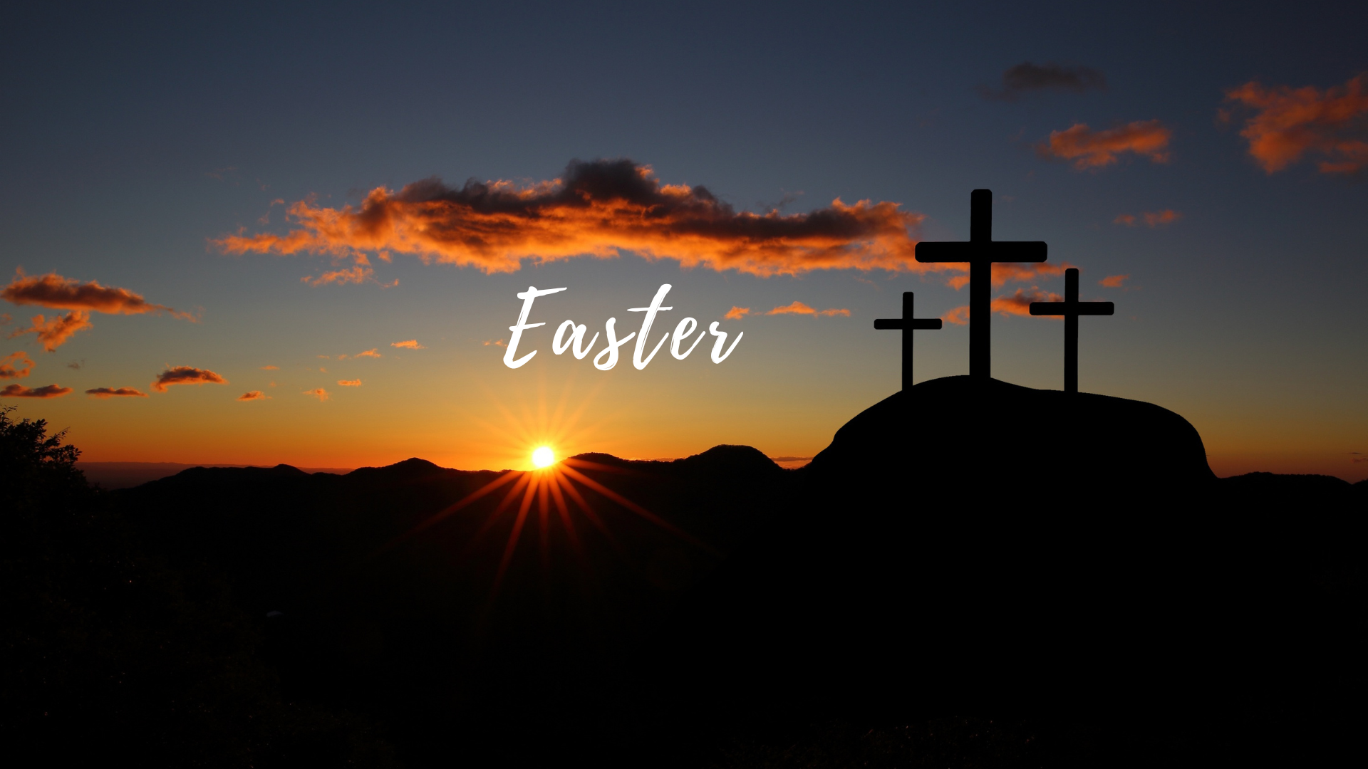 A silhouette of three crosses on a hill with the sun behind them.