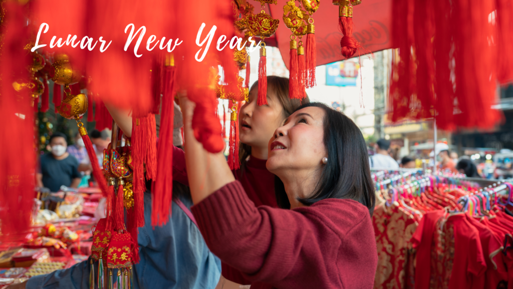 Two women looking at red lanterns in a chinese market.