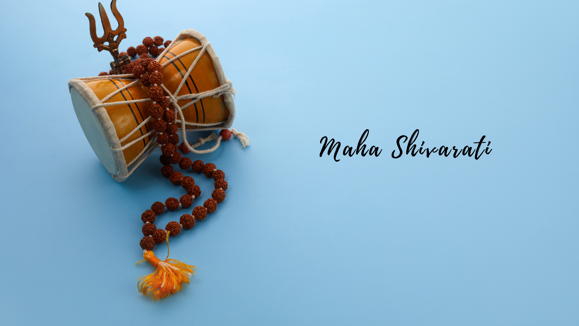 Two small traditional indian drums (tabla) with a rudraksha mala (prayer beads) and a trident (trishul) symbol lying on a blue background with the text .